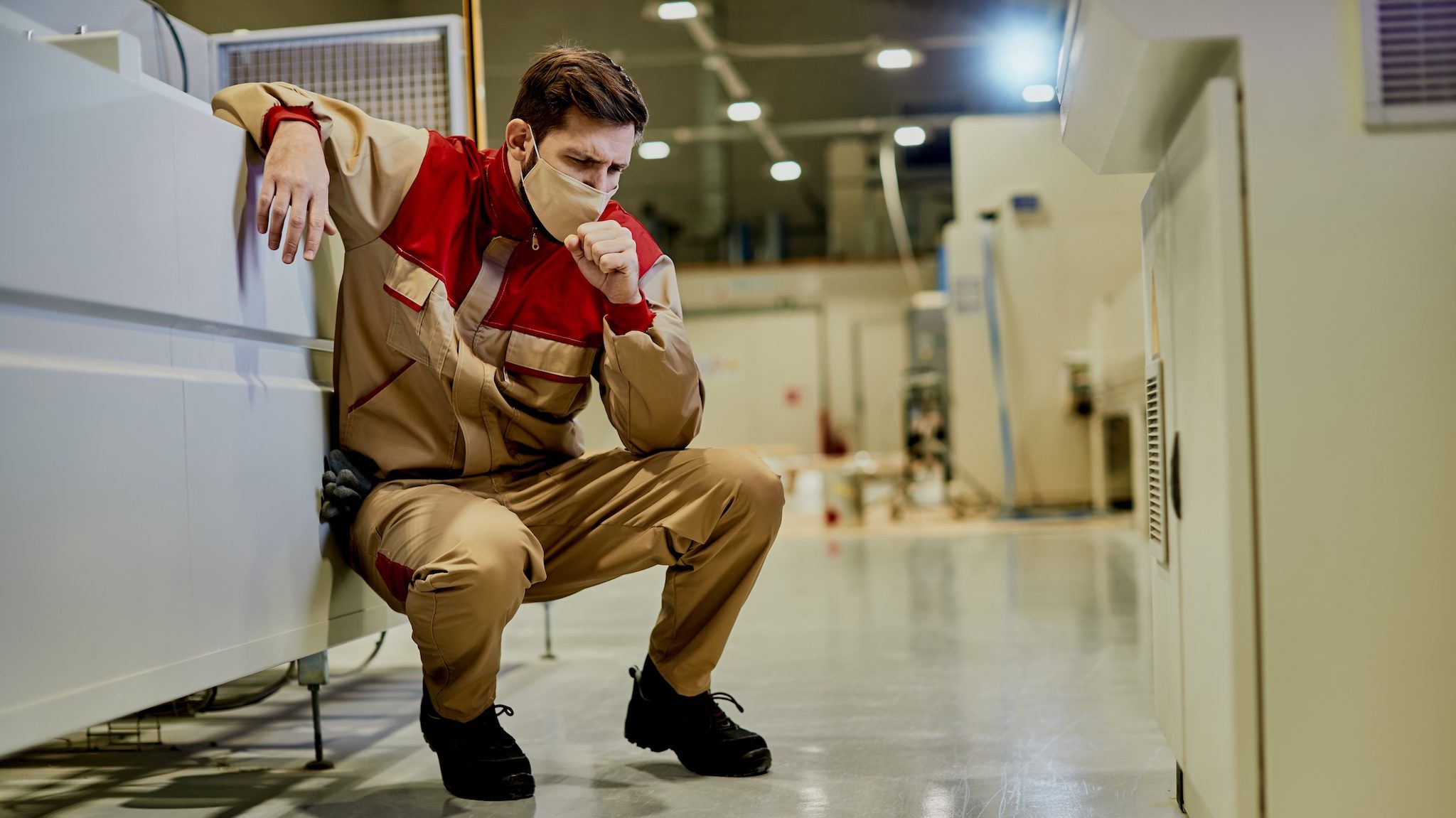 Factory workers wearing masks cough due to poor air quality, dust and chemicals. Dust binding (suppression) with humidification is the safest solution.